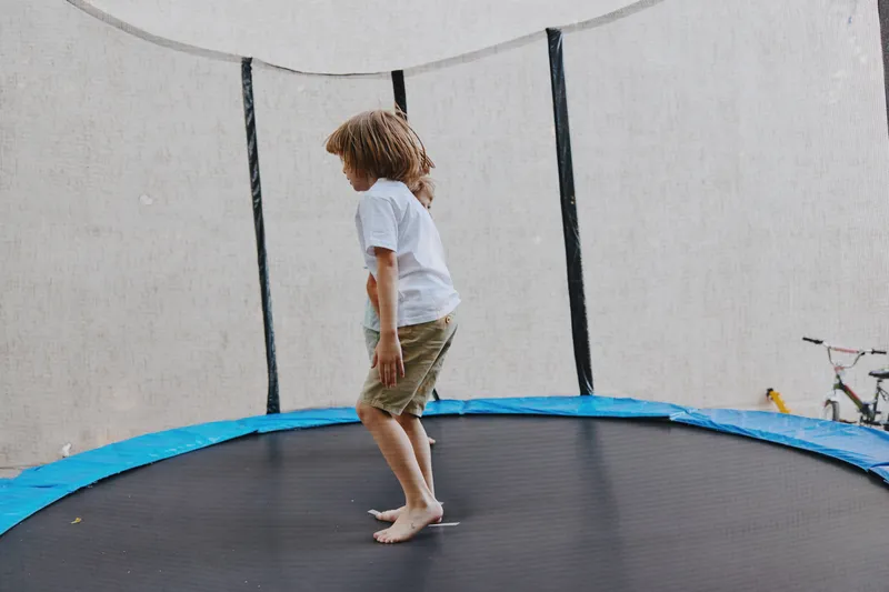 Active boy playing on a trampoline with excitement, enjoying the thrill of bouncing, capturing the essence of childhood joy and outdoor fun.