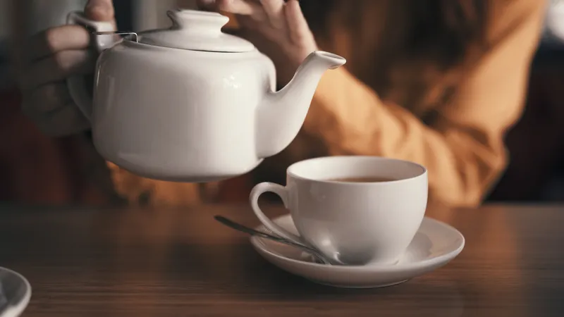 Чай в заварочном чайнике и кружке на столе в кафе, завтрак