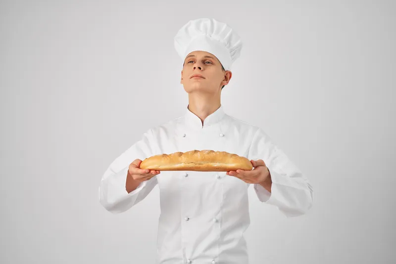 Мужчина в поварской одежде, профессионал с багетом в руках, свежий продукт, работа