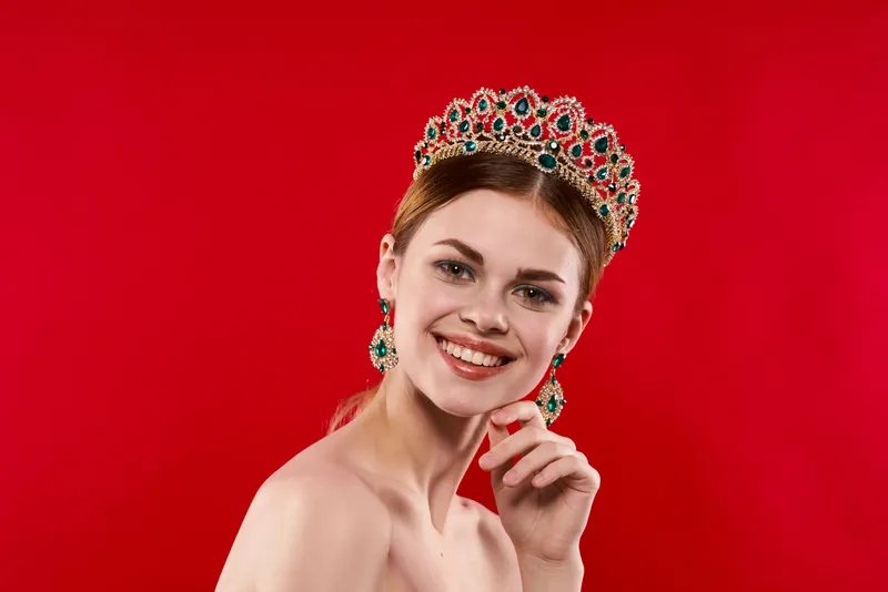 Жизнерадостная женщина с обнаженными плечами, украшениями и короной