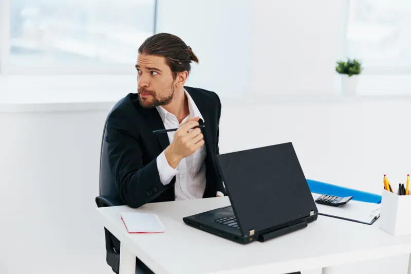 Офисный работник выполняет офисную работу, держа в руках синюю папку с документами и используя технологии