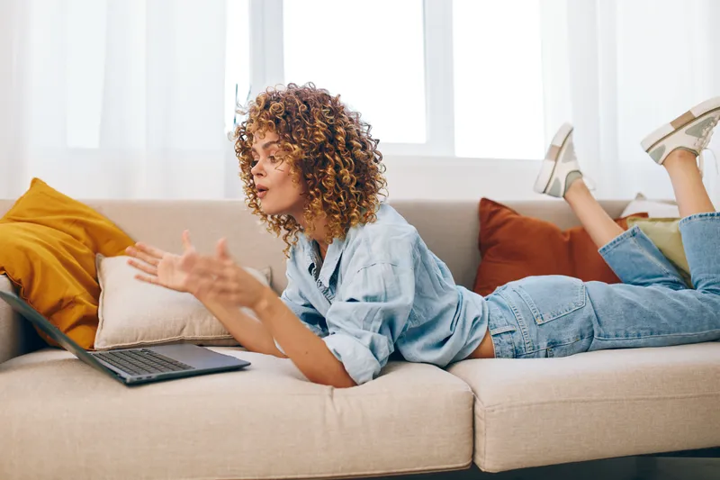 Улыбающаяся женщина работает фрилансером за ноутбуком в уютном домашнем кабинете