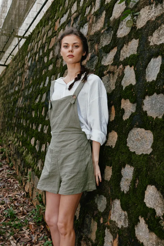A young woman in a stylish outfit poses against a textured stone wall, exuding confidence and casual elegance, perfect for fashion and lifestyle themes
