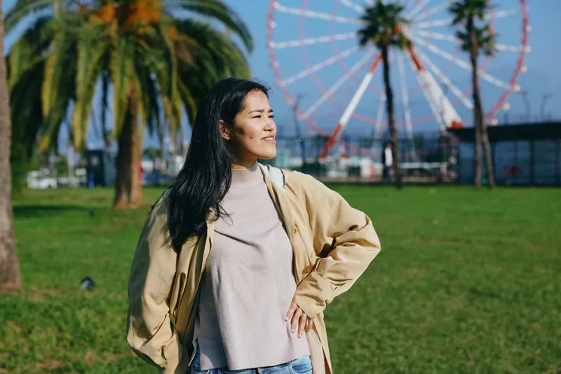 woman, outdoor, park, ferris wheel, smile, casual, jacket, sunlight, leisure, scenery, fashion, nature, day, breeze, happiness, travel, freedom, relaxed, carefree, summer, greenery, amusement, ride,