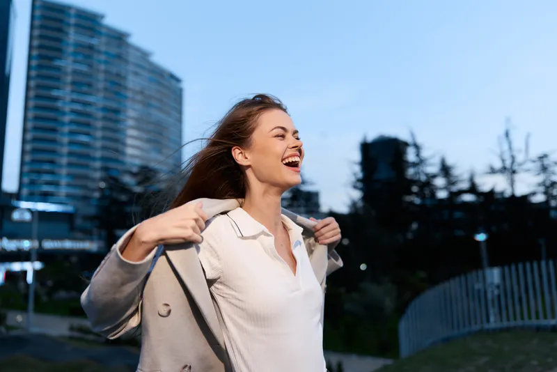 Confident businesswoman smiling outdoors in evening light, dressed in professional attire, embodying empowerment and success.