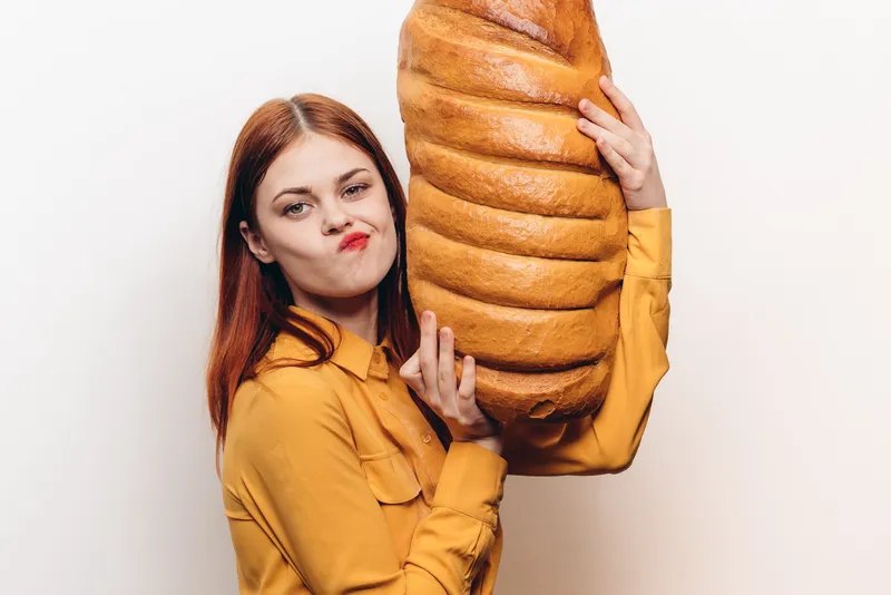 Женщина с батоном в руках на светлом фоне