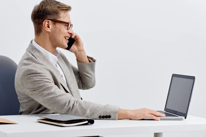 smiling man working with laptop talking on mobile phone smart home technology digital nomad concept in modern office white background