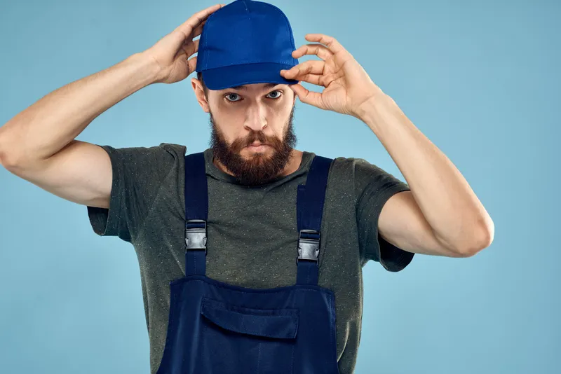 Мужчина в рабочей униформе, профессиональный рабочий образ жизни, служба доставки на синем фоне