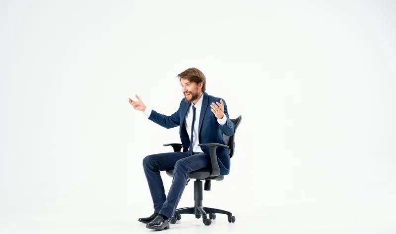 Эмоциональный бизнесмен в офисном кресле работает на светлом фоне