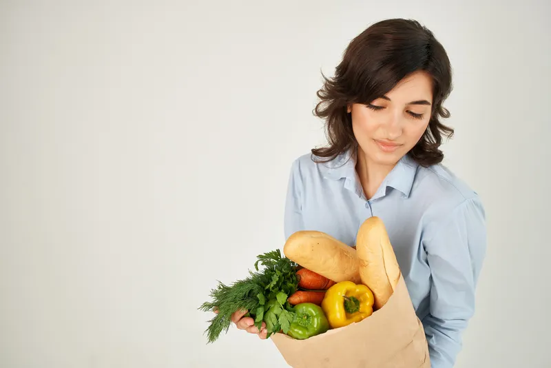 Женщина в синих рубашках с пакетом овощей для доставки продуктов