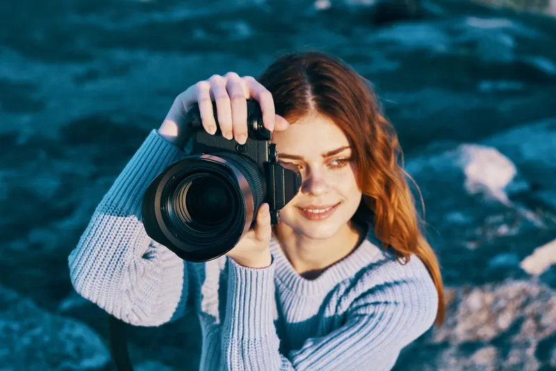 Крупный план профессиональной фотографии симпатичной женщины-фотографа на фоне скалистых гор
