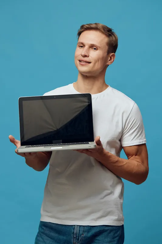 Full body smiling man holding open laptop computer isolated on blue background studio portrait. People technology concept