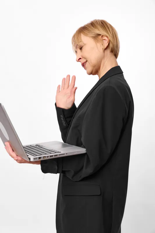 Businesswoman with laptop in black suit, office, isolated on white, stop and refusal gesture, side profile, concerned expression, communication pause