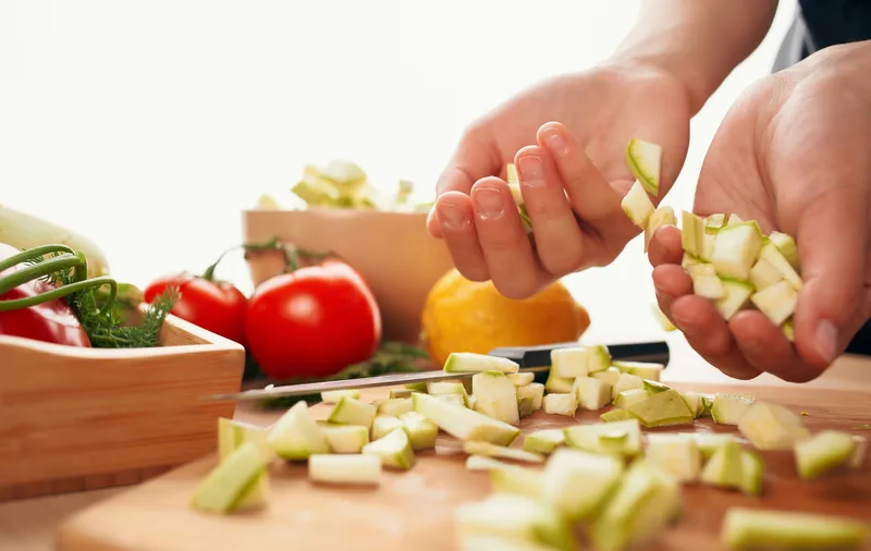 Нарезка свежих овощей на разделочной доске на кухне