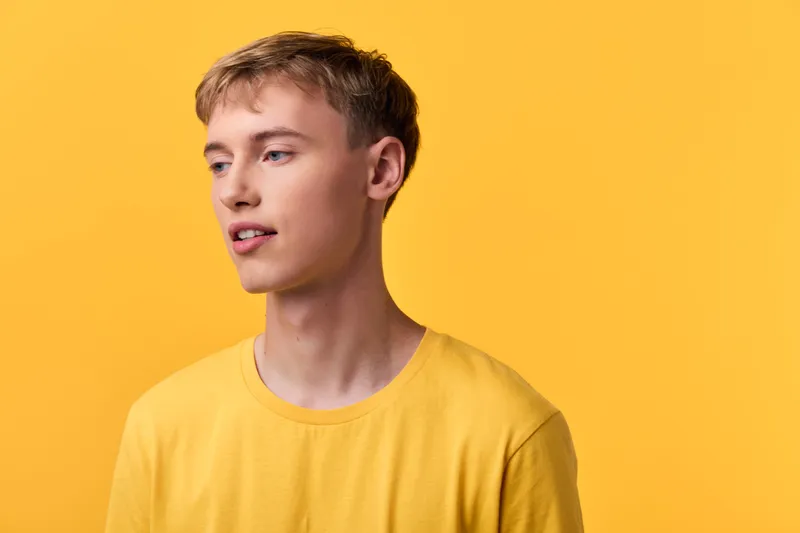 Man, young, casual, yellow, background, studio, clothing, tshirt on model in a warm yellow setting for fashion, lifestyle and minimalist vibe