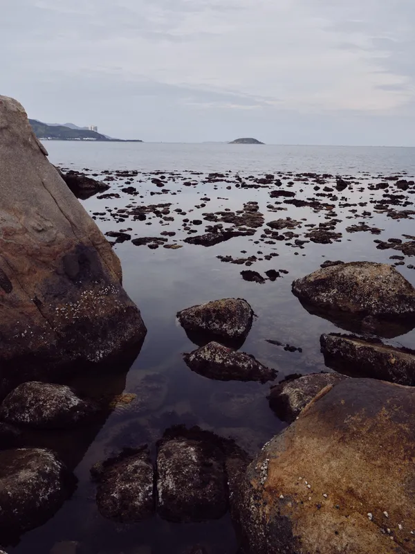 Tranquil coastal landscape with calm waters, rocky shore, and gentle waves creating an atmosphere of serenity and peace
