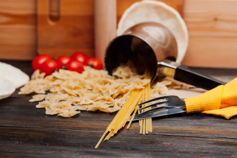 Макароны, посыпанные на столе, помидоры, итальянская кухня, приготовление еды