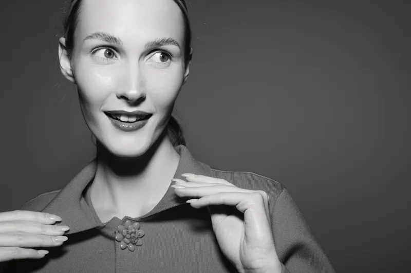 Portrait of a young white woman with fair skin smiling and looking aside in black and white studio photo. Concept of beauty, expression, and vintage fashion style.