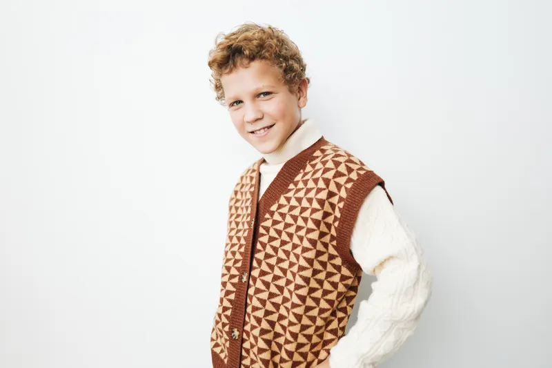 Authentic portrait of a student in a vintage knit vest, casual school day style, confident pose, genuine mood, and a simple lifestyle scene capturing everyday life and play.