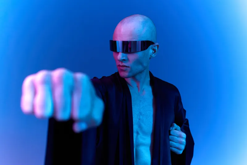 Futuristic man in stylish glasses striking a confident pose against a vibrant neon background. A blend of bold colors creates a striking visual impact.