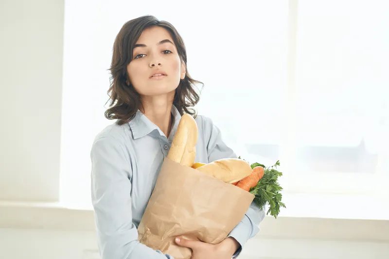 Веселая брюнетка с пакетом овощей, доставка продуктов, домохозяйка