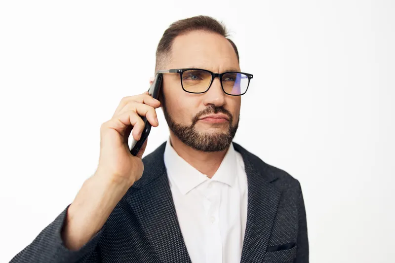 Business professional man on a phone with a confident, focused expression, isolated colored background, conveying urgency and clear communication in a corporate setting.