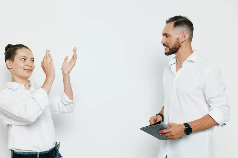 A confident business professional man stands with a colleague against a clean isolated colored background, showing engagement, focus, and leadership through open gestures.
