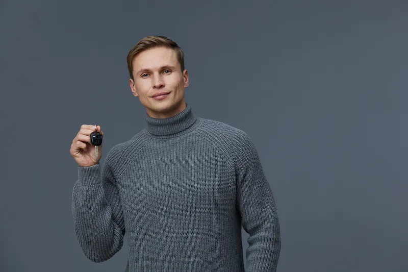 Young caucasian man wearing gray knitted turtleneck holding smart watch smiling confident isolated on gray background digital detox concept health wellness gadget