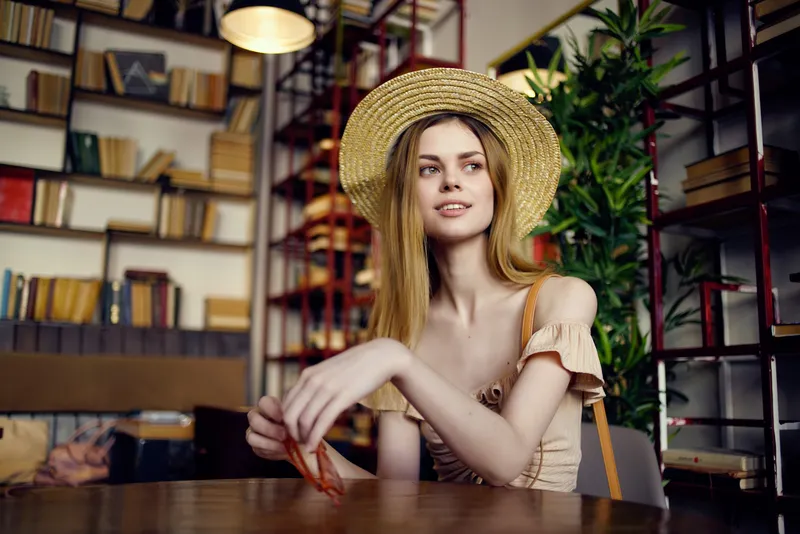 Красивая женщина читает книгу в кафе, стильно одетая
