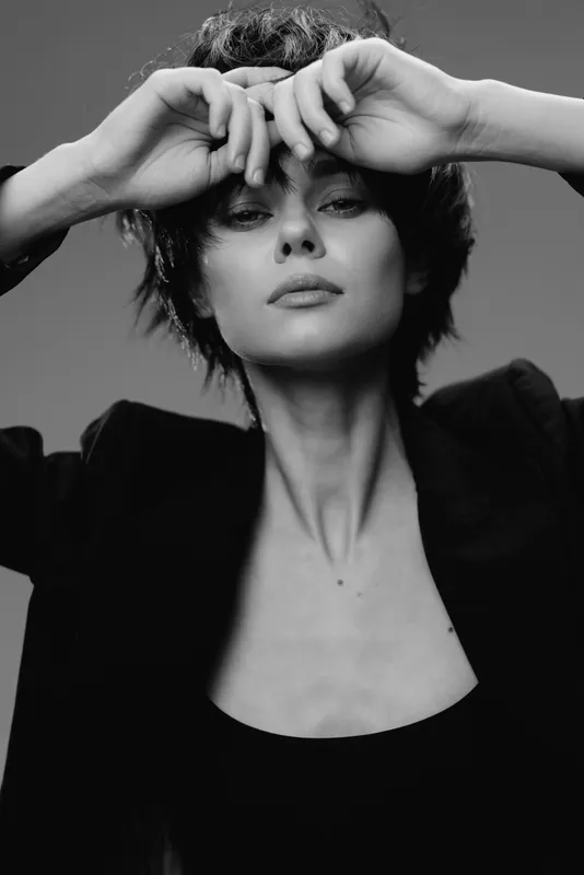 Black and white portrait of a confident woman with short hair wearing a blazer, expressing elegance and mystery.