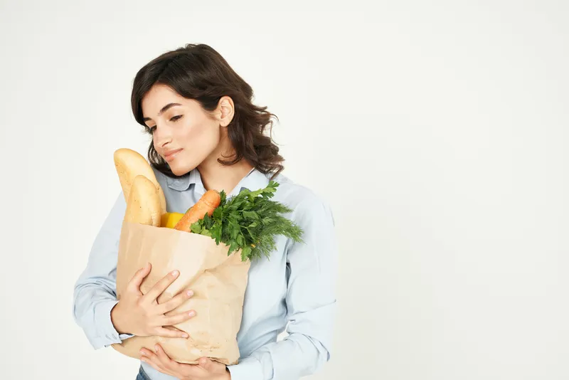 Улыбающаяся женщина с пакетом продуктов в супермаркете