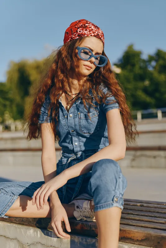Modern boho-western denim street style woman wearing blue denim outfit and large sunglasses in outdoor urban setting, film color aesthetic with relaxed lifestyle vibe.