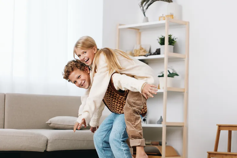 Authentic lifestyle moment showing a couple in a playful game indoors, capturing genuine emotion, connection, and a cozy, sunlit home setting.