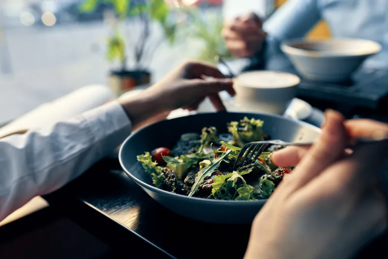 Свежий салат на тарелке, вкусная диетическая еда, вилка в руке, женские руки, кафе