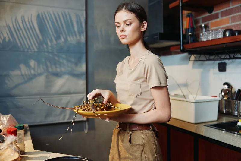 Женщина готовит вкусное блюдо на современной кухне, держа миску с едой перед плитой
