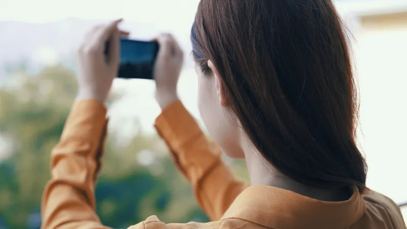 Женщина на улице с телефоном в руках фотографирует на камеру
