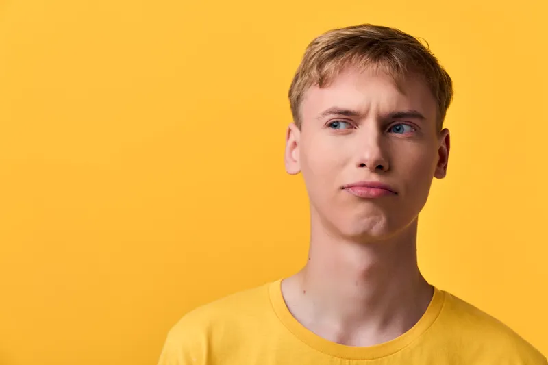 Thinking, man, puzzled expression against vibrant yellow background, casual t shirt, introspective mood, studio shot, minimalist scene, curiosity and doubt shaping a thoughtful moment