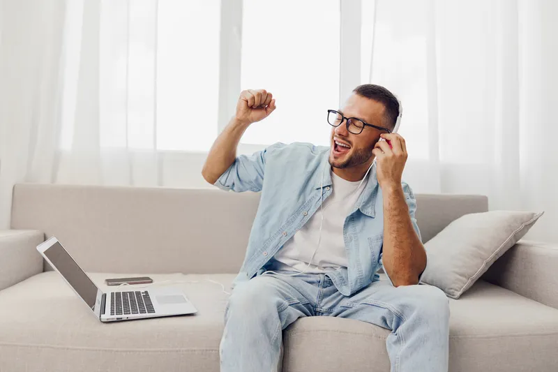 Joyful man enjoying music during digital detox at home, embracing emotional minimalism and nurturing mental health in a comfortable setting.