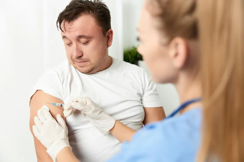 Женщина-врач крупным планом делает мужчине укол вакцины в руку