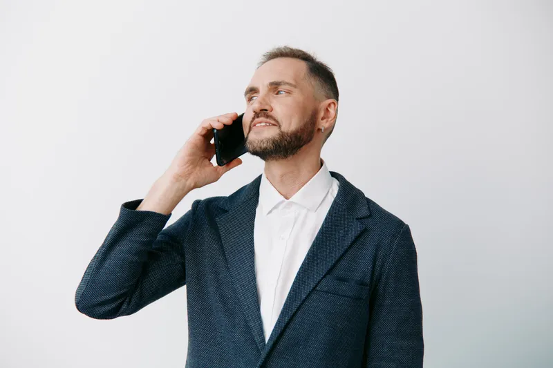 A professional businessman on an isolated colored background, talking on a mobile phone. He shows confident focus and calm determination, signaling leadership and clear communication.