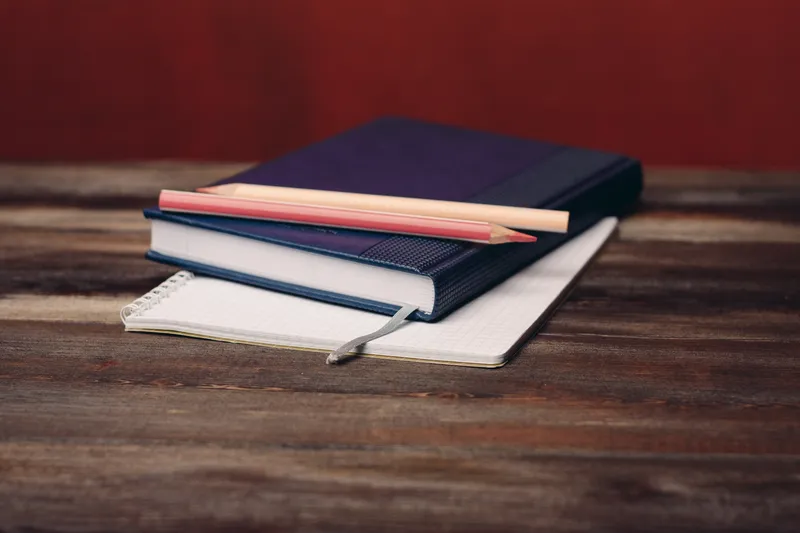 Книги, блокноты и ручки на деревянном столе — карандаш, офисные письменные принадлежности