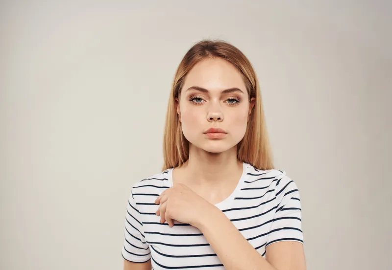Портрет женщины с blond-волосами на бежевом фоне, крупный план, обрезанный вид