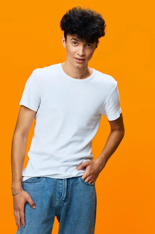 young man in white t-shirt posing confidently against bright orange background, casual style, modern fashion, youthful energy, studio portrait