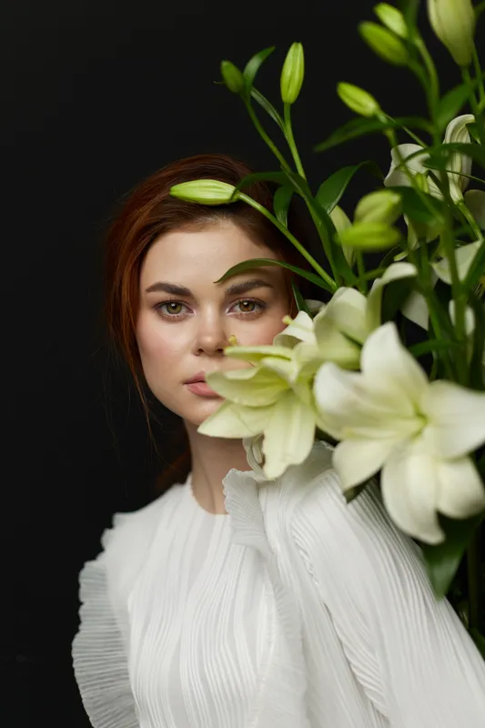 Young woman with flowers, expressing serenity and beauty, showcasing a soft color palette with a focus on white and green tones, perfect for wellness themes