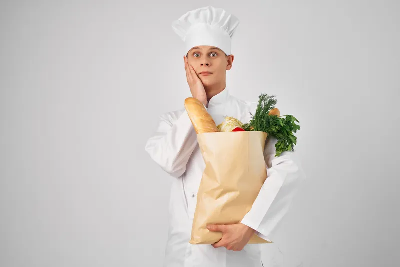 Эмоциональный мужчина-шеф-повар с пакетом продуктов