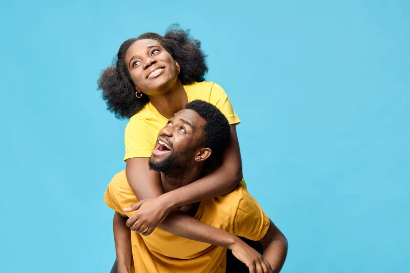 Joyful couple in matching yellow outfits against a vibrant blue background, exuding happiness and love, perfect for seasonal campaigns and lifestyle themes