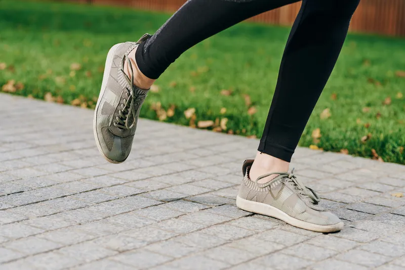 Ноги в кроссовках и черных леггинсах, бег на длинные дистанции в парке на природе