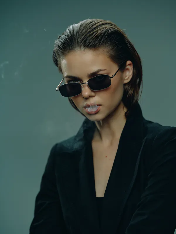 Stylish woman wearing sunglasses and black clothing with a confident expression and modern edgy look.