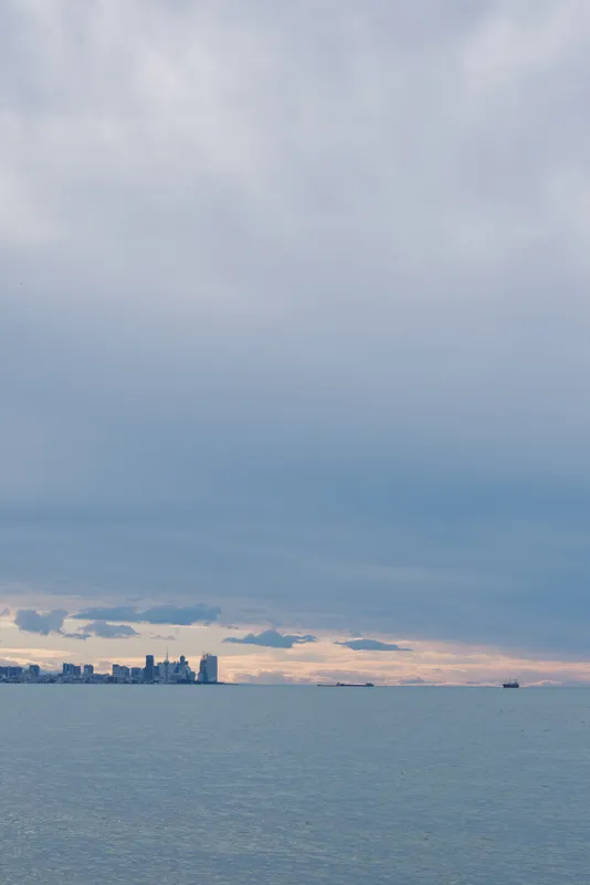 Sea and distant skyline on a calm horizon with soft clouds and a subtle sunset glow over open water, tranquil seascape for nature or travel