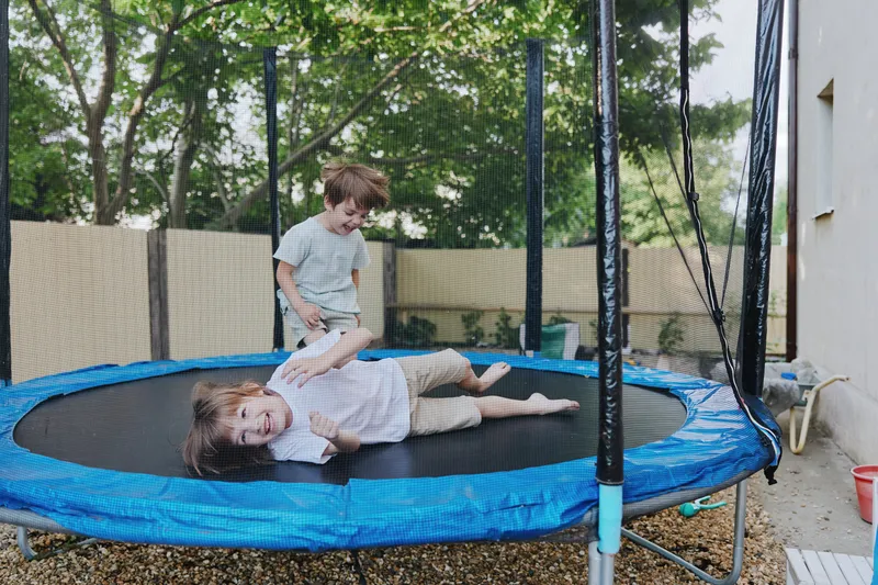 Playful children jumping on a trampoline, enjoying a sunny day in the garden, filled with laughter and joy, perfect for family activities and outdoor fun.